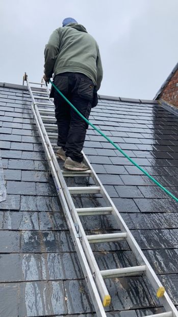 A man is standing on a ladder on top of a roof.