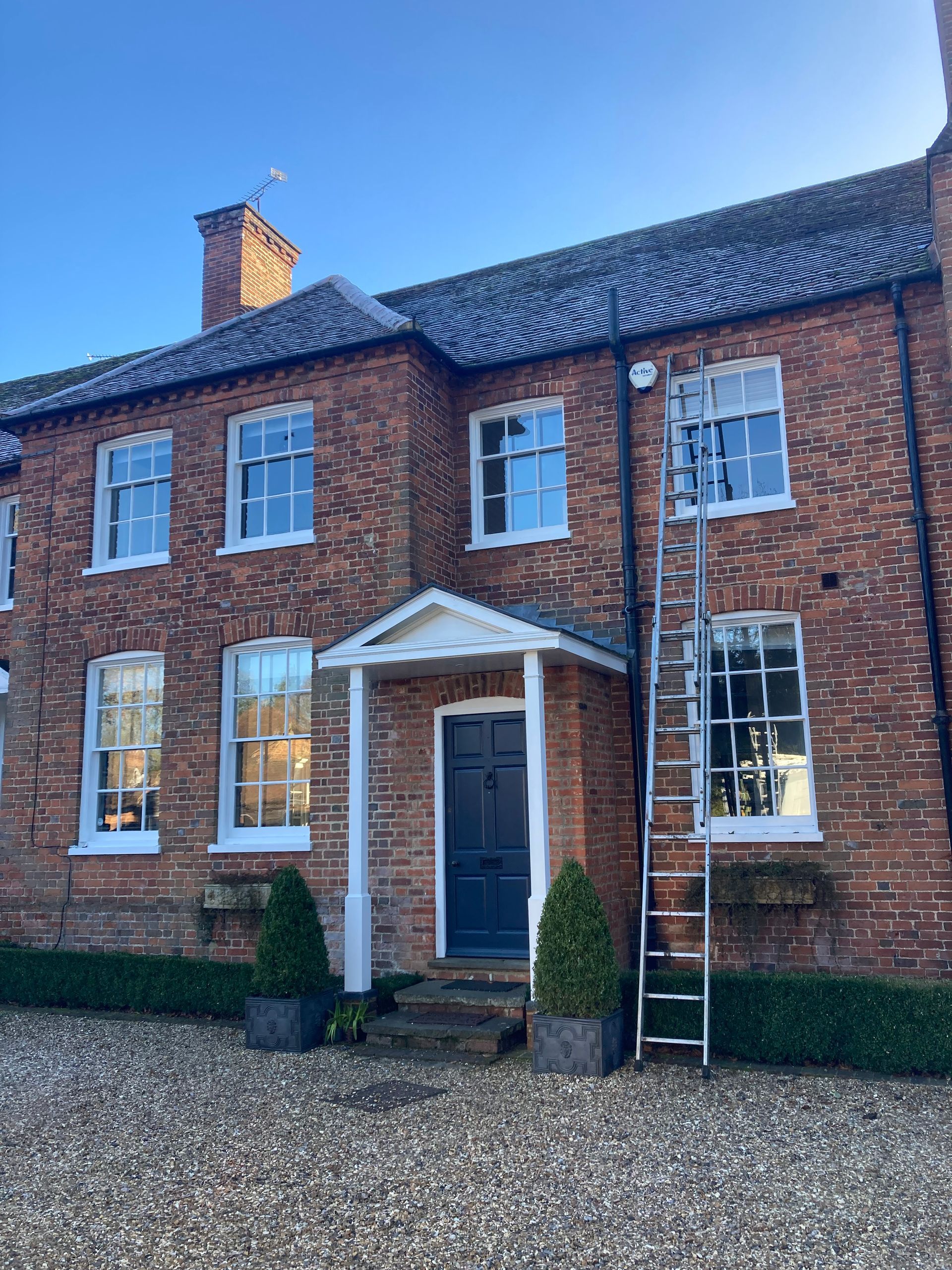 A large brick house with a ladder in front of it.