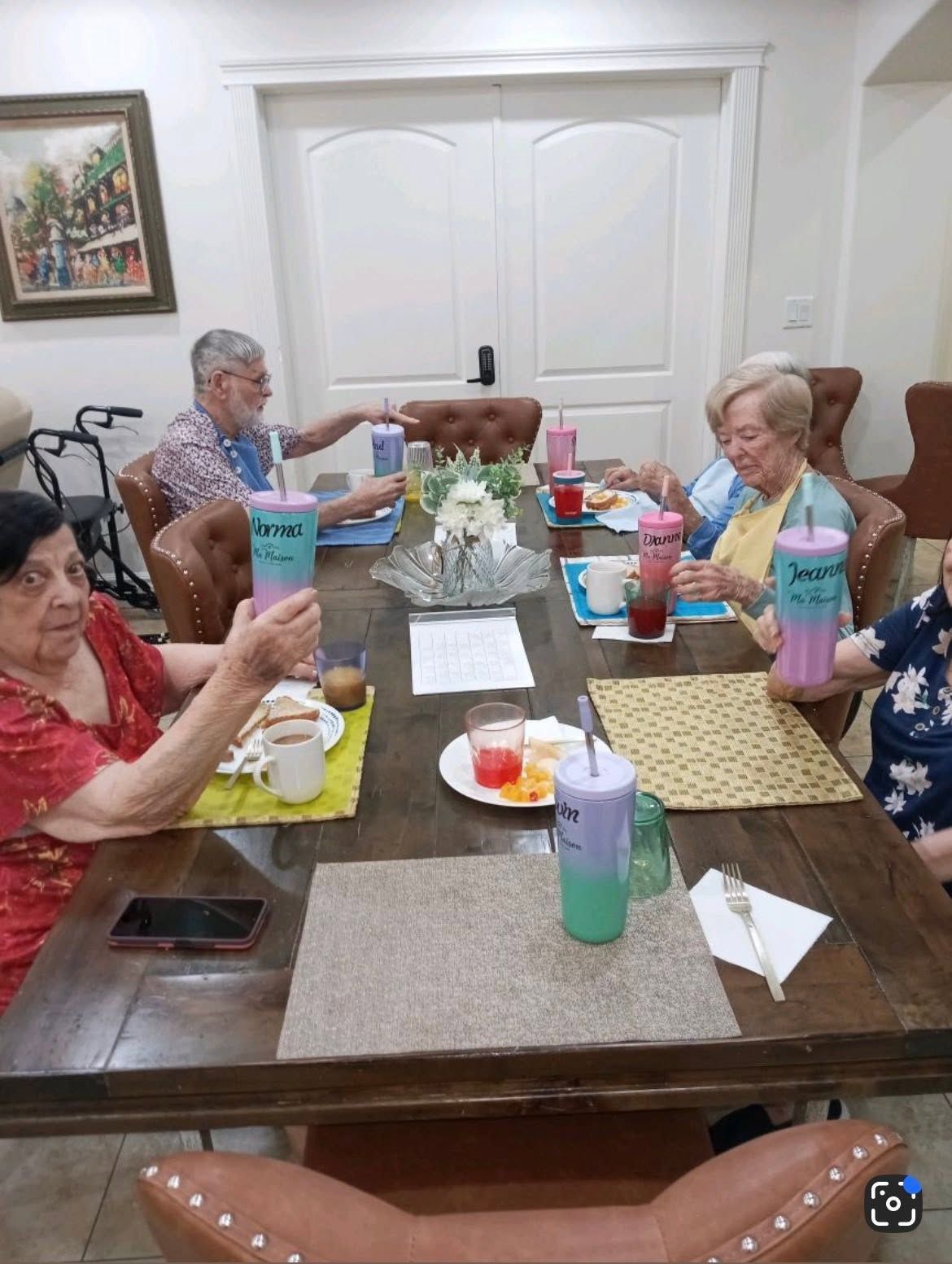 Group of people seated around a dining table, eating and chatting in a bright room.