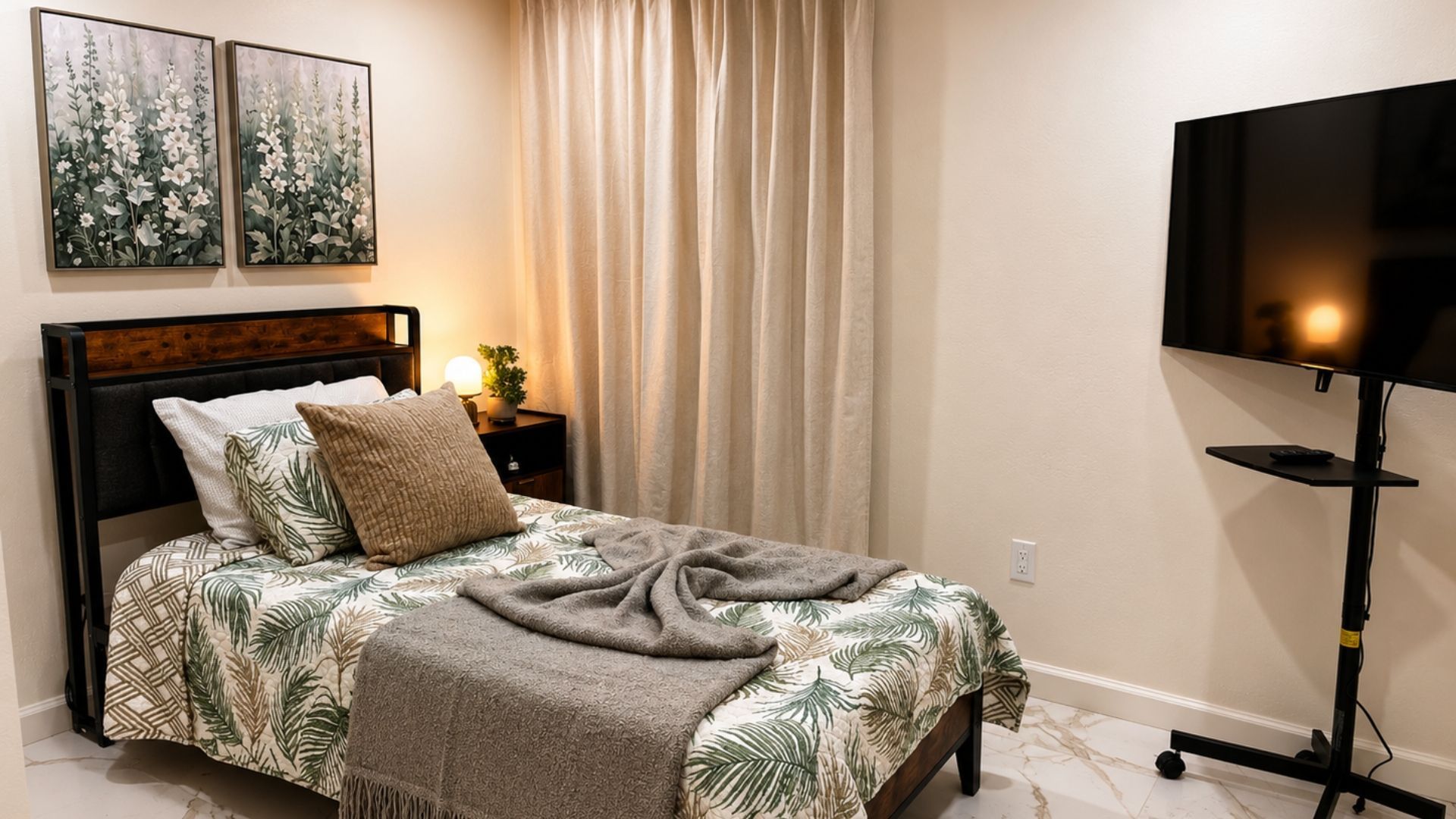 Neat bedroom with a made bed, beige curtains, wall art, and a TV on a stand.