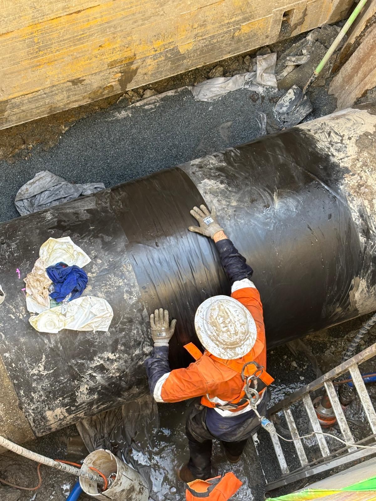 A man is working on a large pipe in the ground.