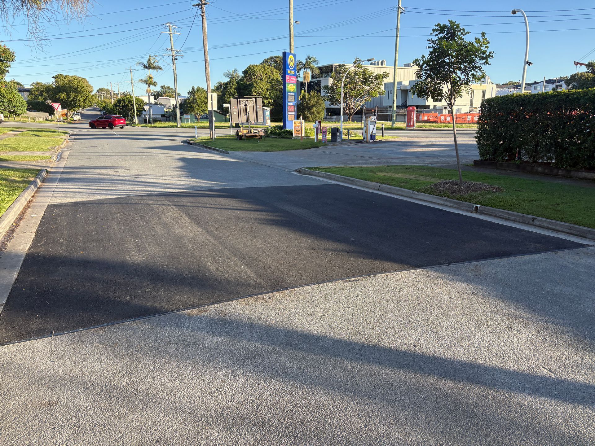 A car is driving down a street next to a grassy area.