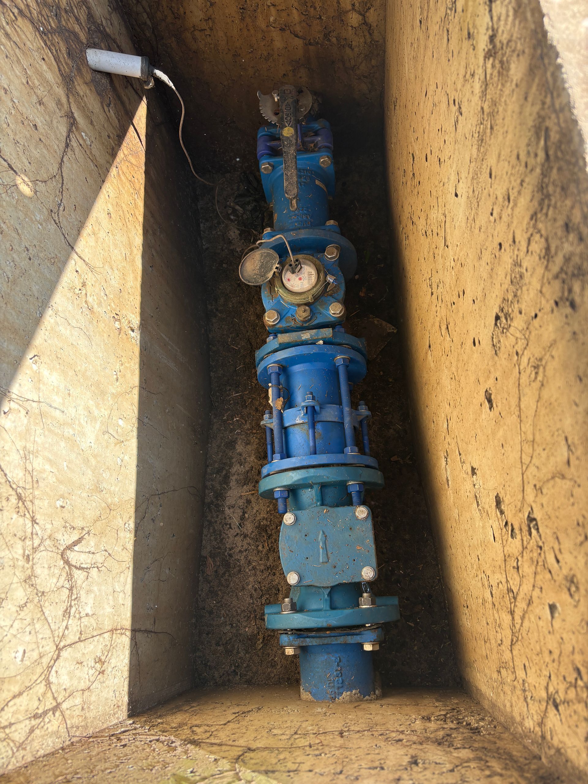 A red excavator is cutting down trees in a field.