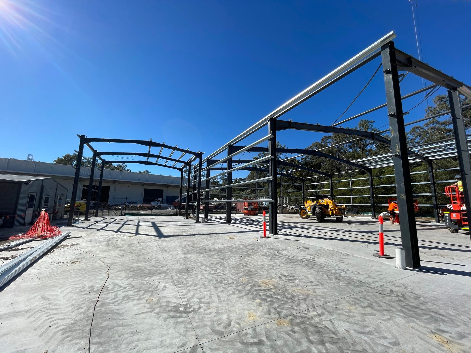 A large metal structure is being built in a parking lot.