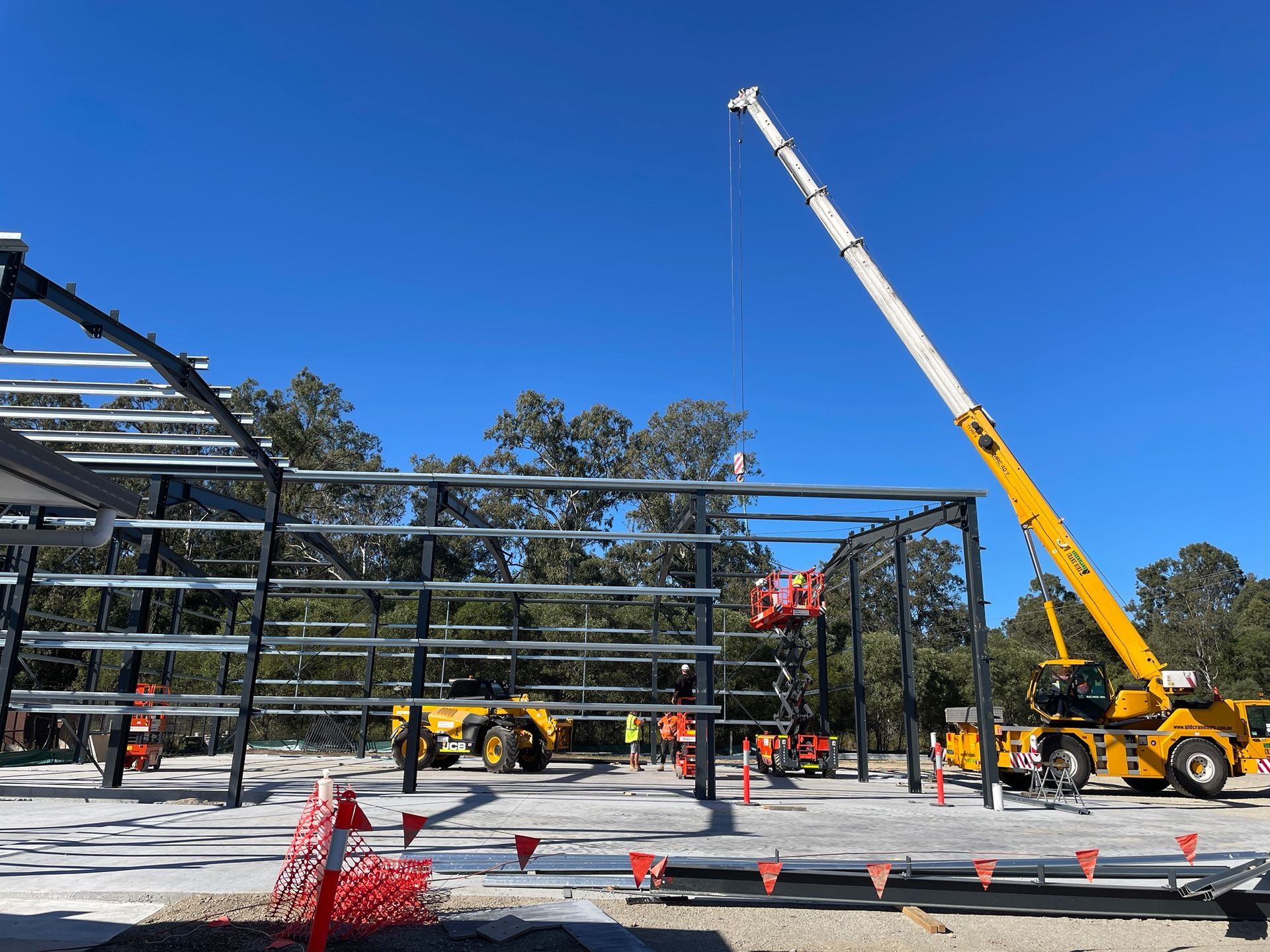 A large yellow crane is lifting a metal structure on a construction site.