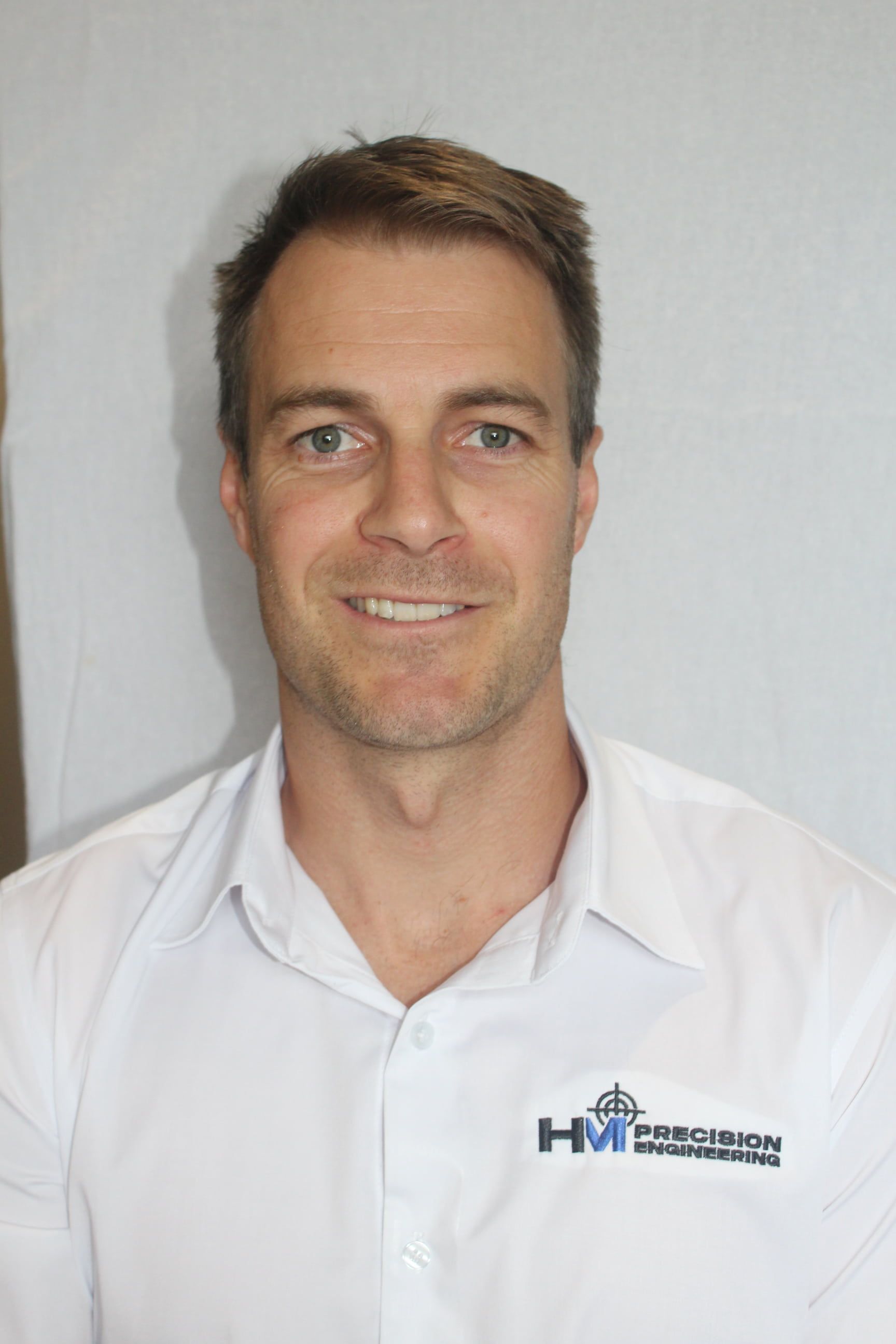 A man in a white shirt is smiling for the camera.