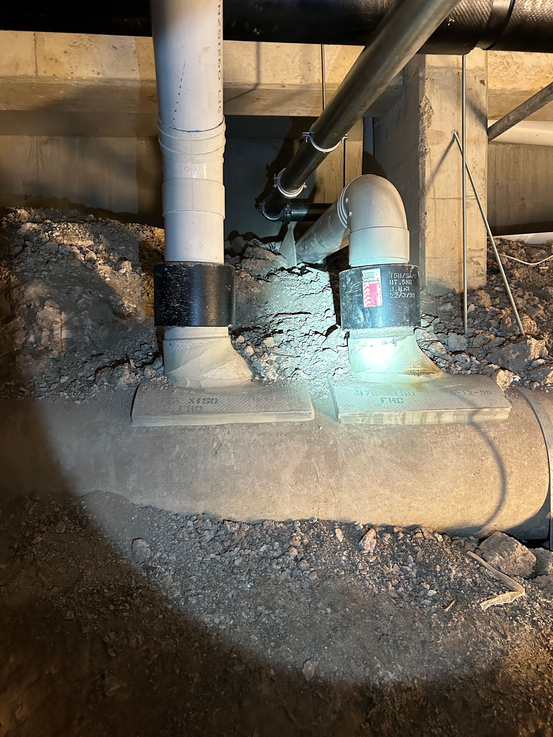A close up of a pipe in a basement with a light on it.