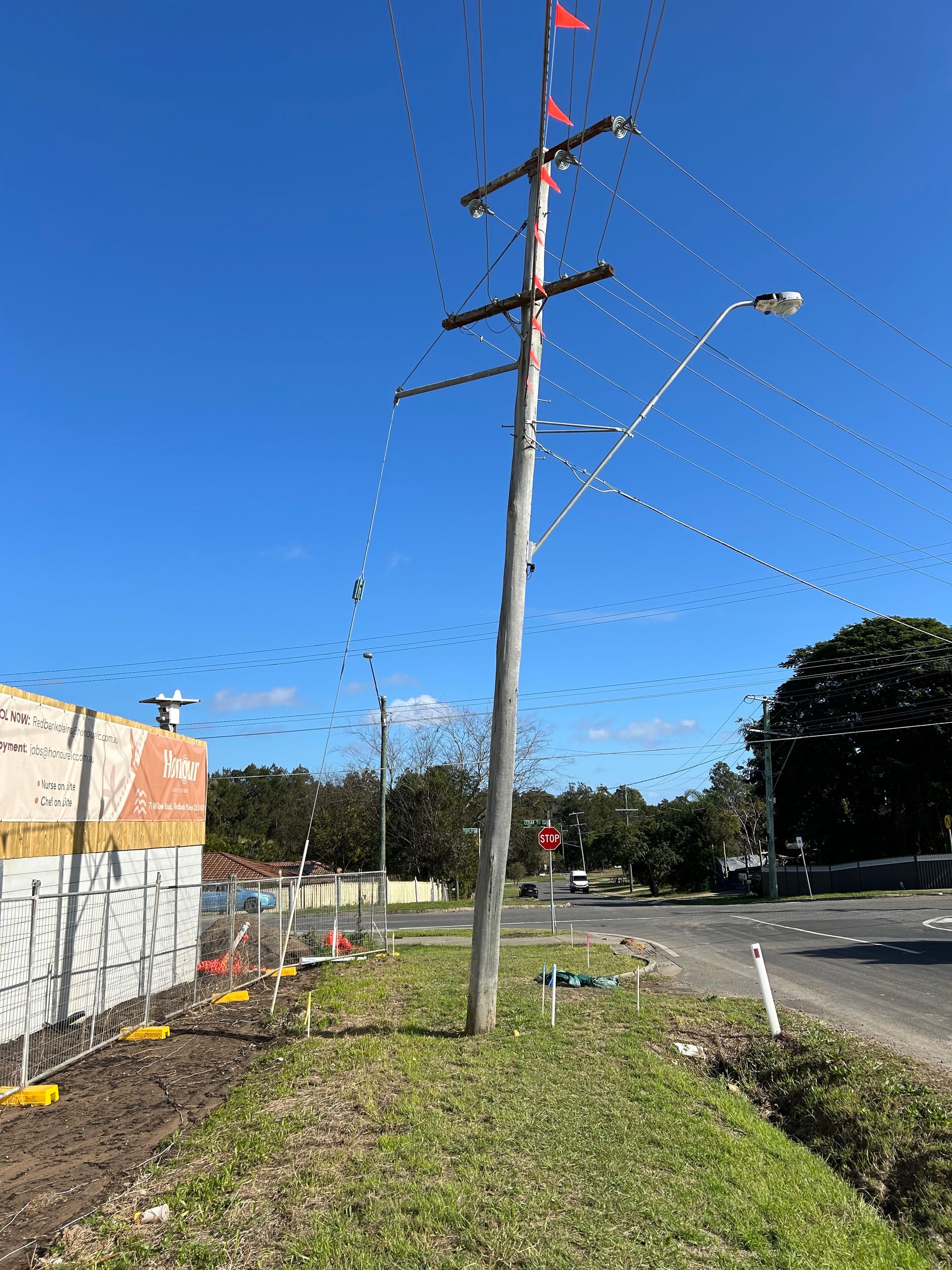 A telephone pole is sitting in the middle of a grassy field next to a road.