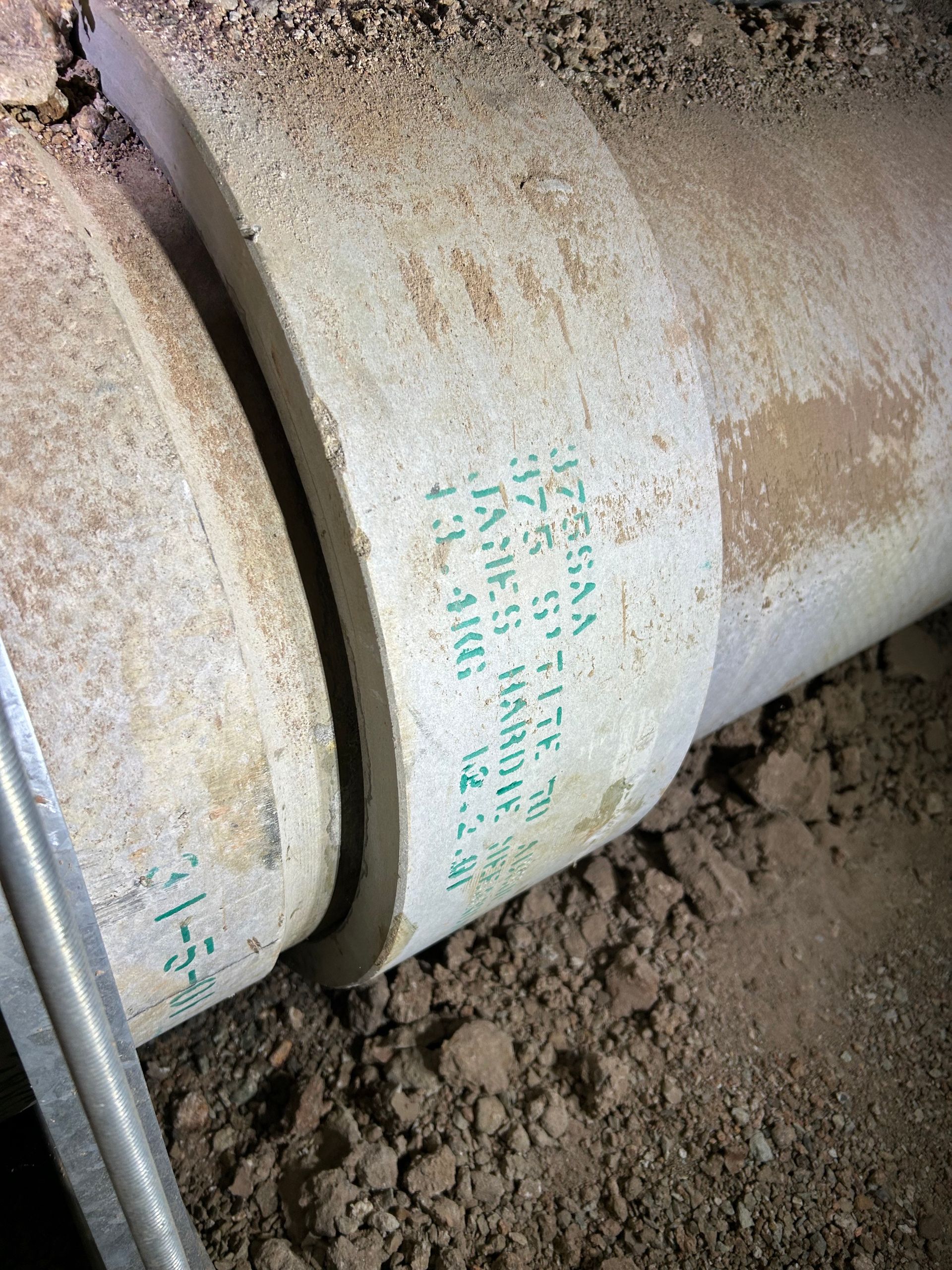 A dirty pvc pipe is laying on the ground.