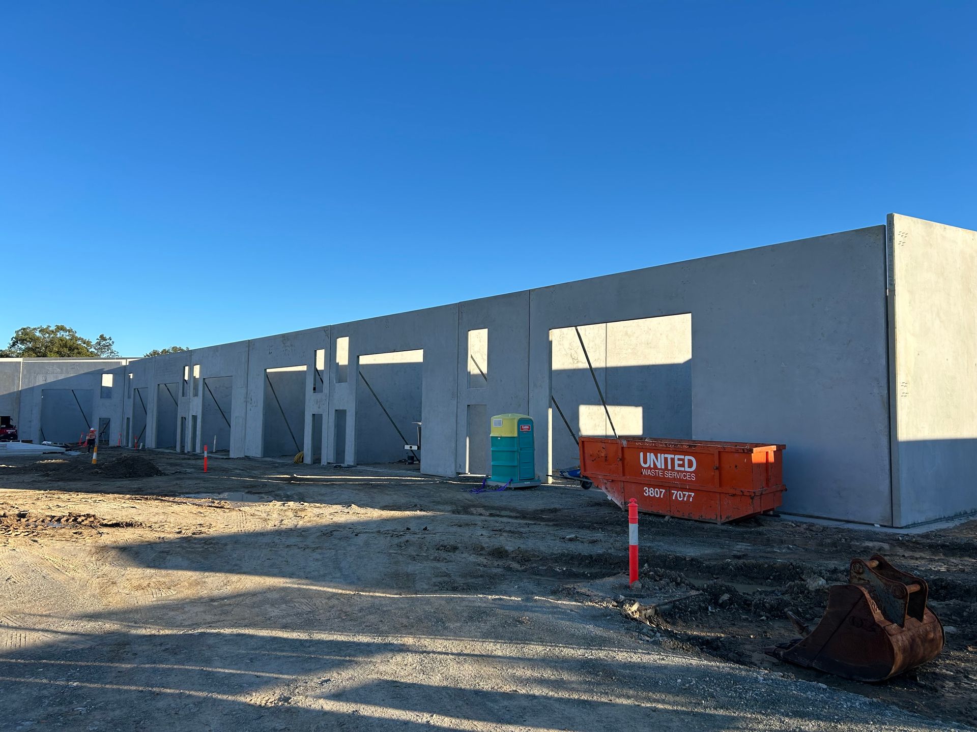A large concrete building is being built in a dirt field.