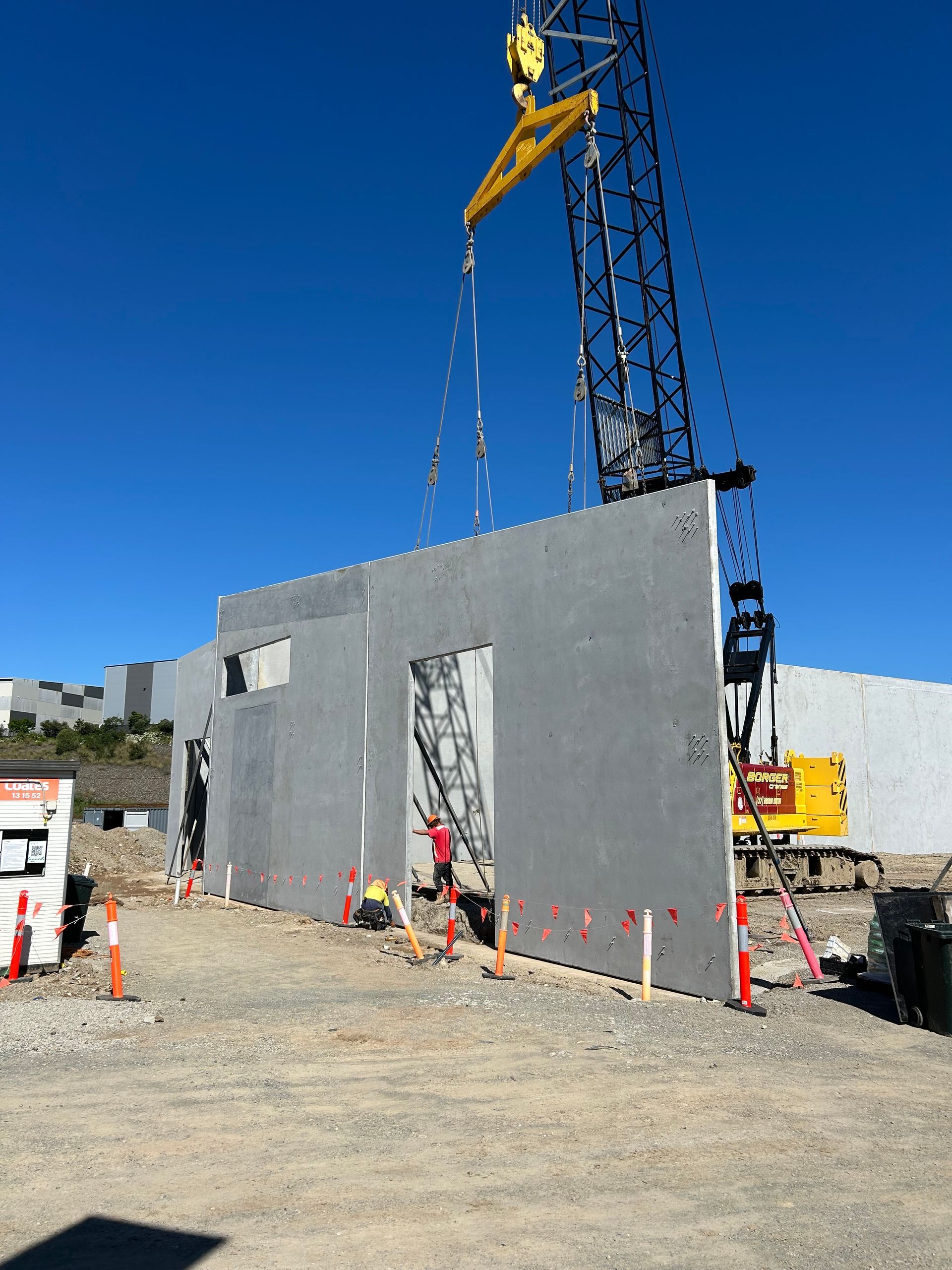 A construction site with a crane lifting a wall
