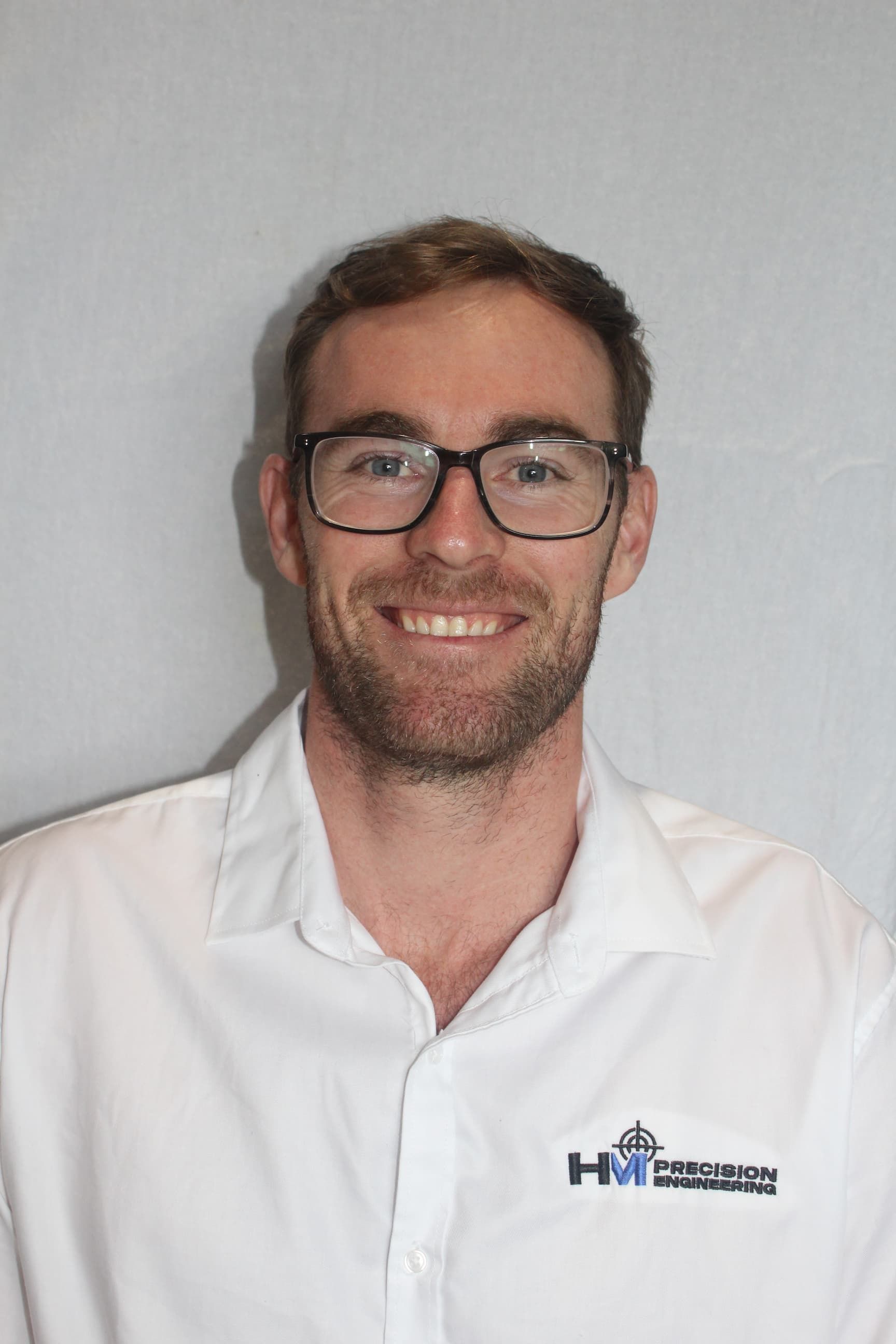 A man wearing glasses and a white shirt is smiling for the camera.