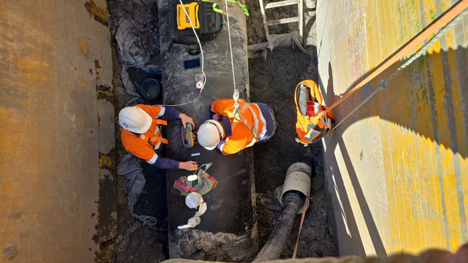 A group of construction workers are working on a pipe.