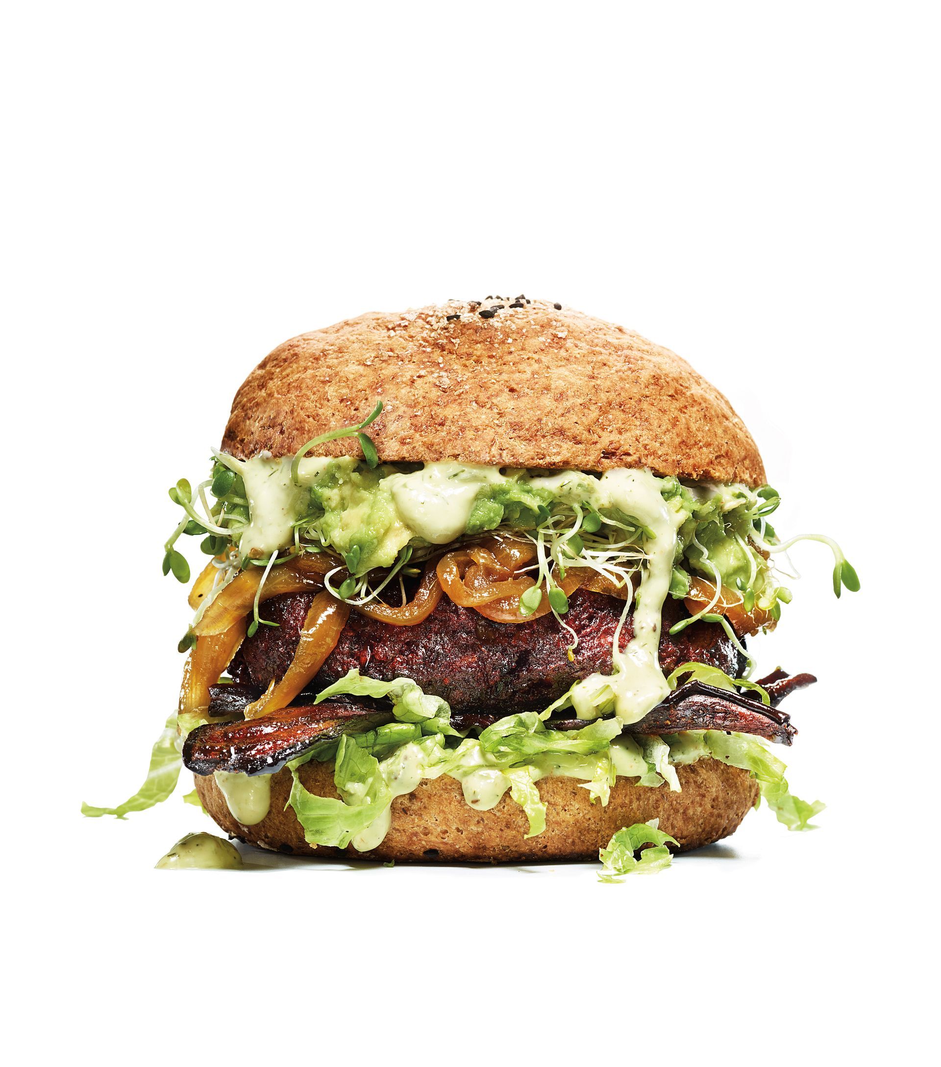 Un hamburger con lattuga, avocado, cipolle e salsa su un panino su uno sfondo bianco.