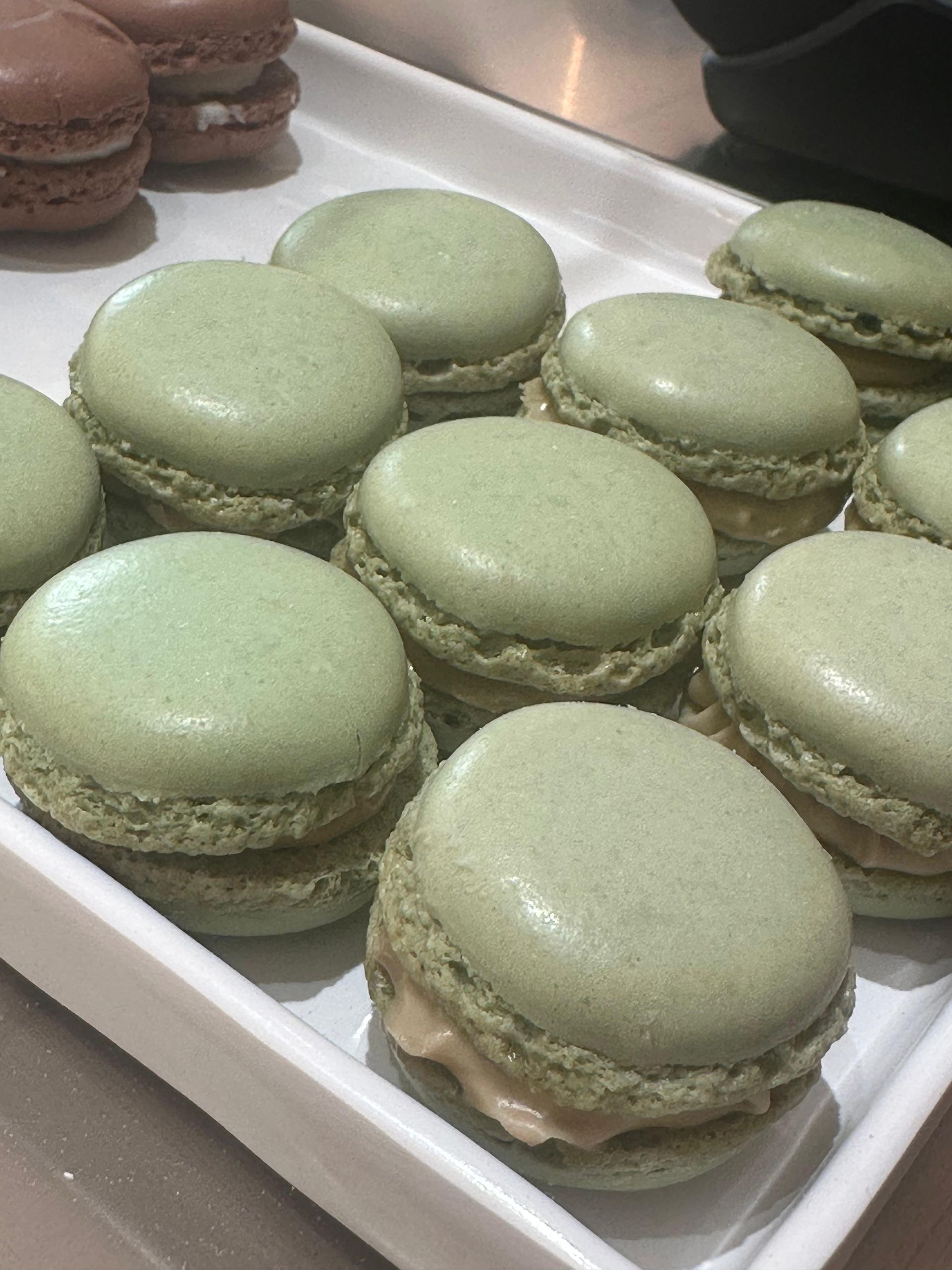 Un vassoio bianco pieno di macaron verdi su un tavolo