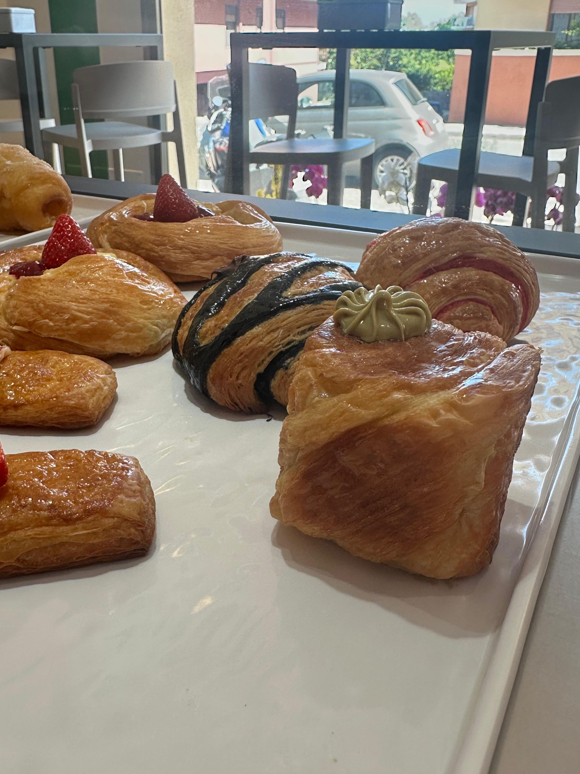 Una varietà di pasticcini sono appoggiati su un vassoio bianco su un tavolo.