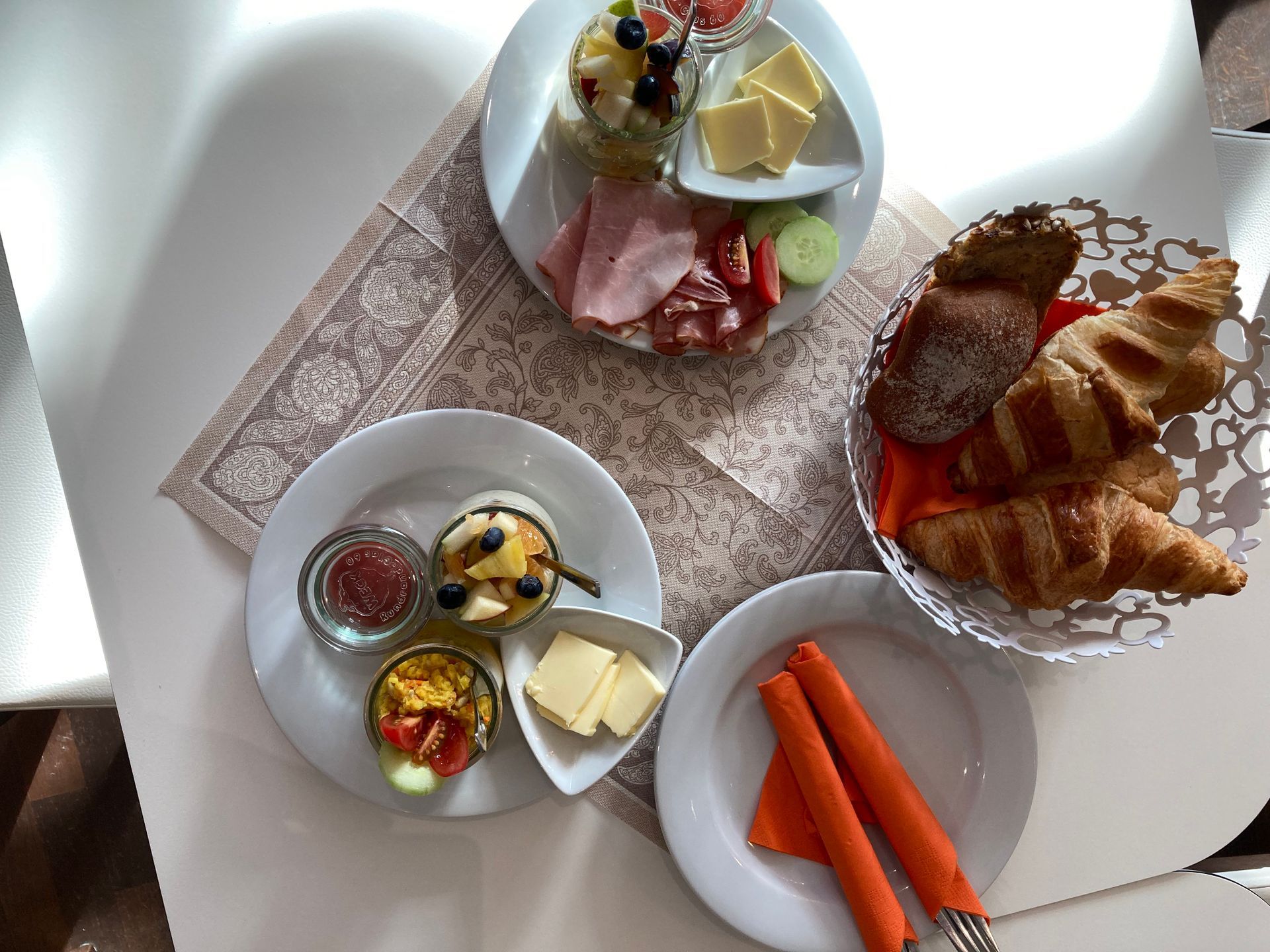 Ein Tisch mit Tellern voller Essen und einem Korb voller Croissants.