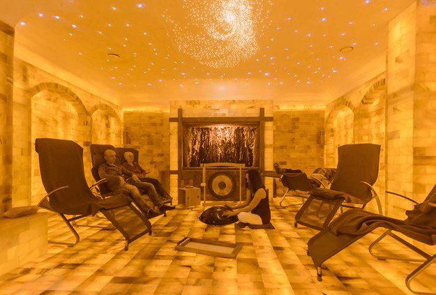 Eine Gruppe von Menschen sitzt auf Stühlen in einem Raum mit einem Fernseher.