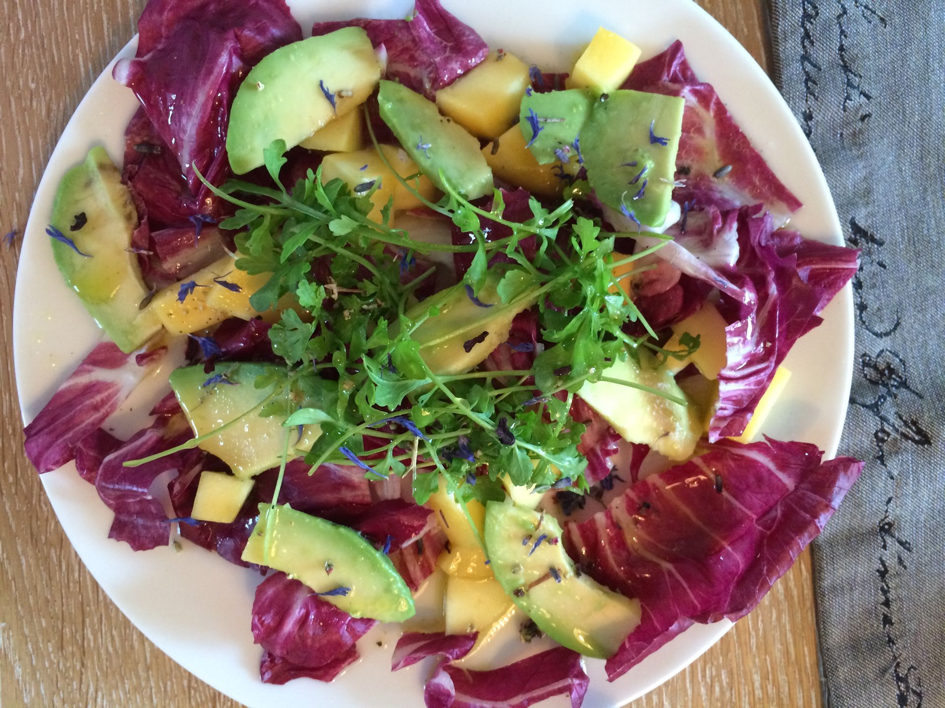 Ein Salat mit Salat, Avocado und Ananas auf einem weißen Teller