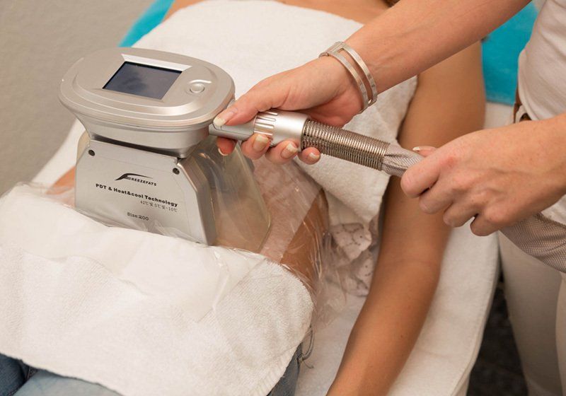 Eine Frau bekommt mit einem Gerät eine Behandlung am Arm.