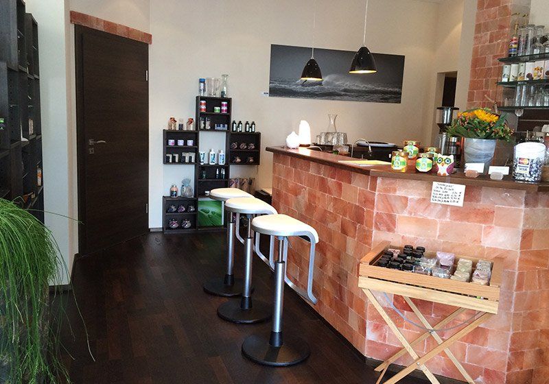 In einem Raum steht eine Reihe Barhocker vor einer Theke.