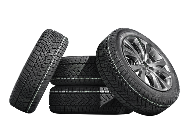 A stack of black vehicle tires with treads, with one mounted on a metallic alloy rim.