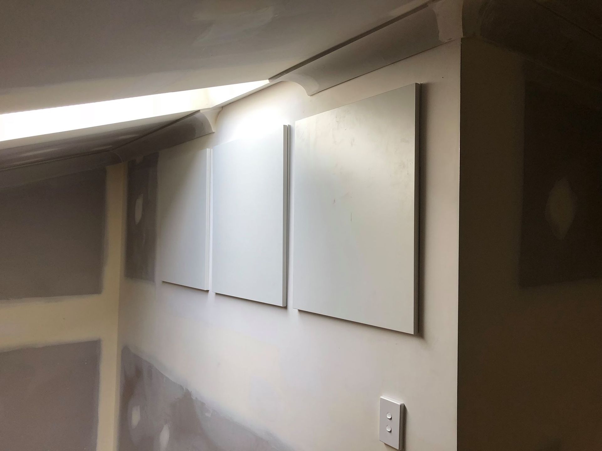 Row of White Canvases Are Hanging on a Wall in a Room — Hancock Construction & Maintenance in Newcastle, NSW
