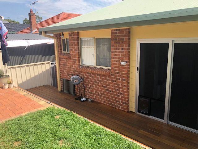 Brick House With a Sliding Glass Door and a Wooden Deck — Hancock Construction & Maintenance in Port Stephens, NSW