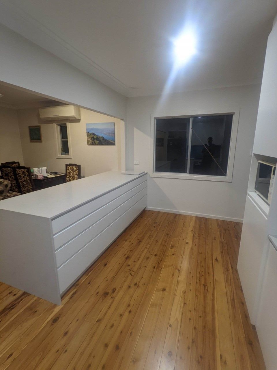 Kitchen With Wooden Floors and White Cabinets and a Large Window — Hancock Construction & Maintenance in Newcastle, NSW