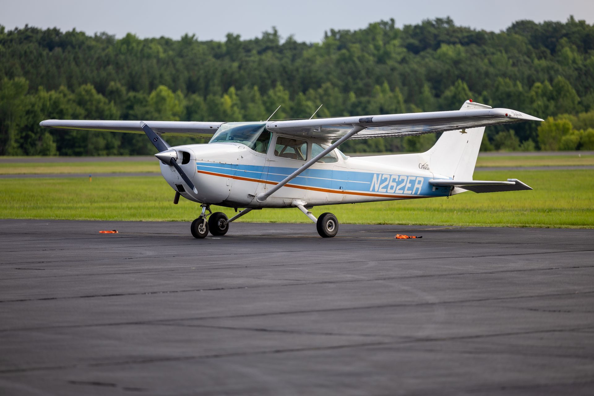 A small plane is sitting on a runway with trees in the background.