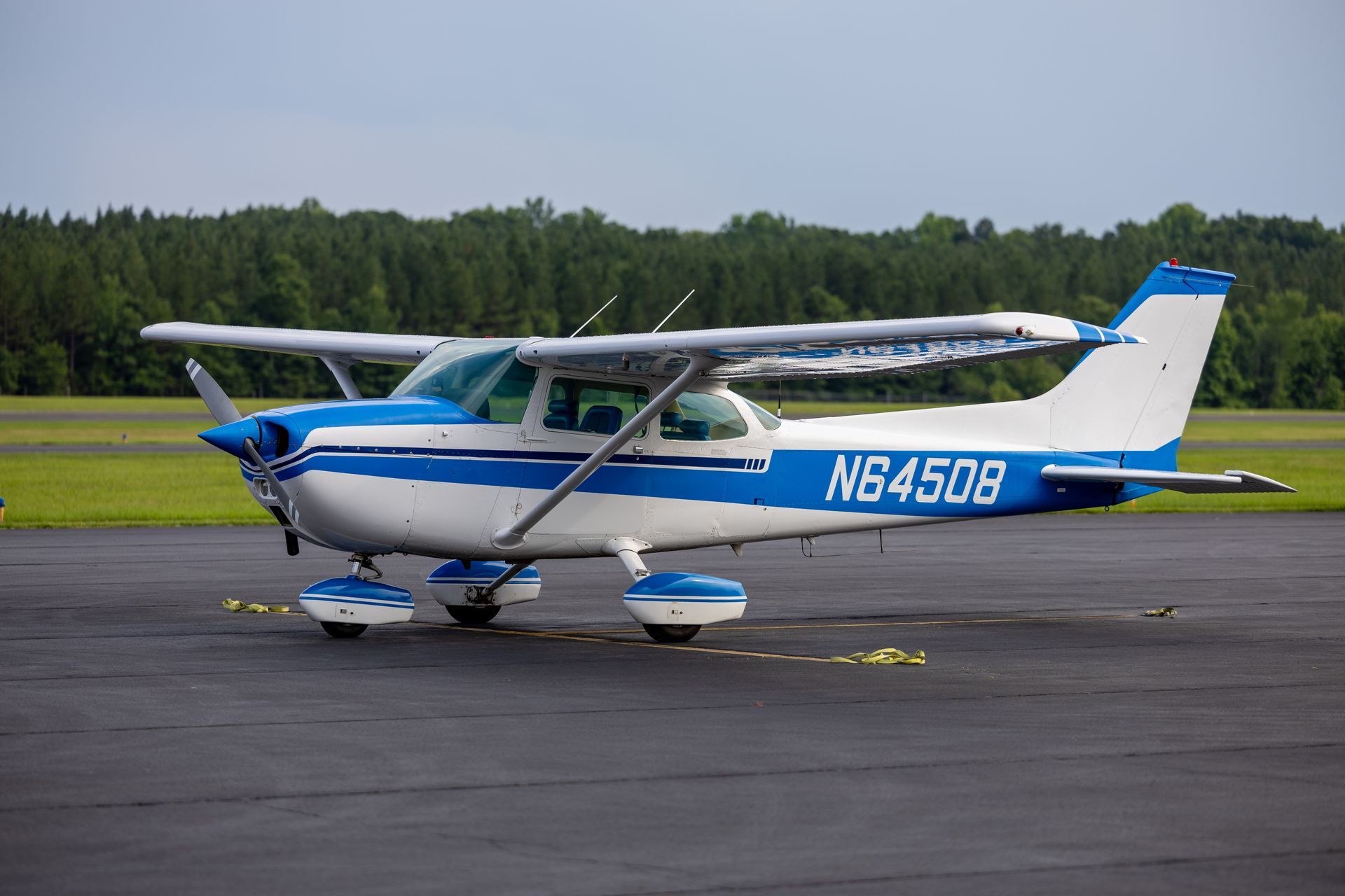 A small blue and white plane with the number n64508 on the side is parked on a runway.