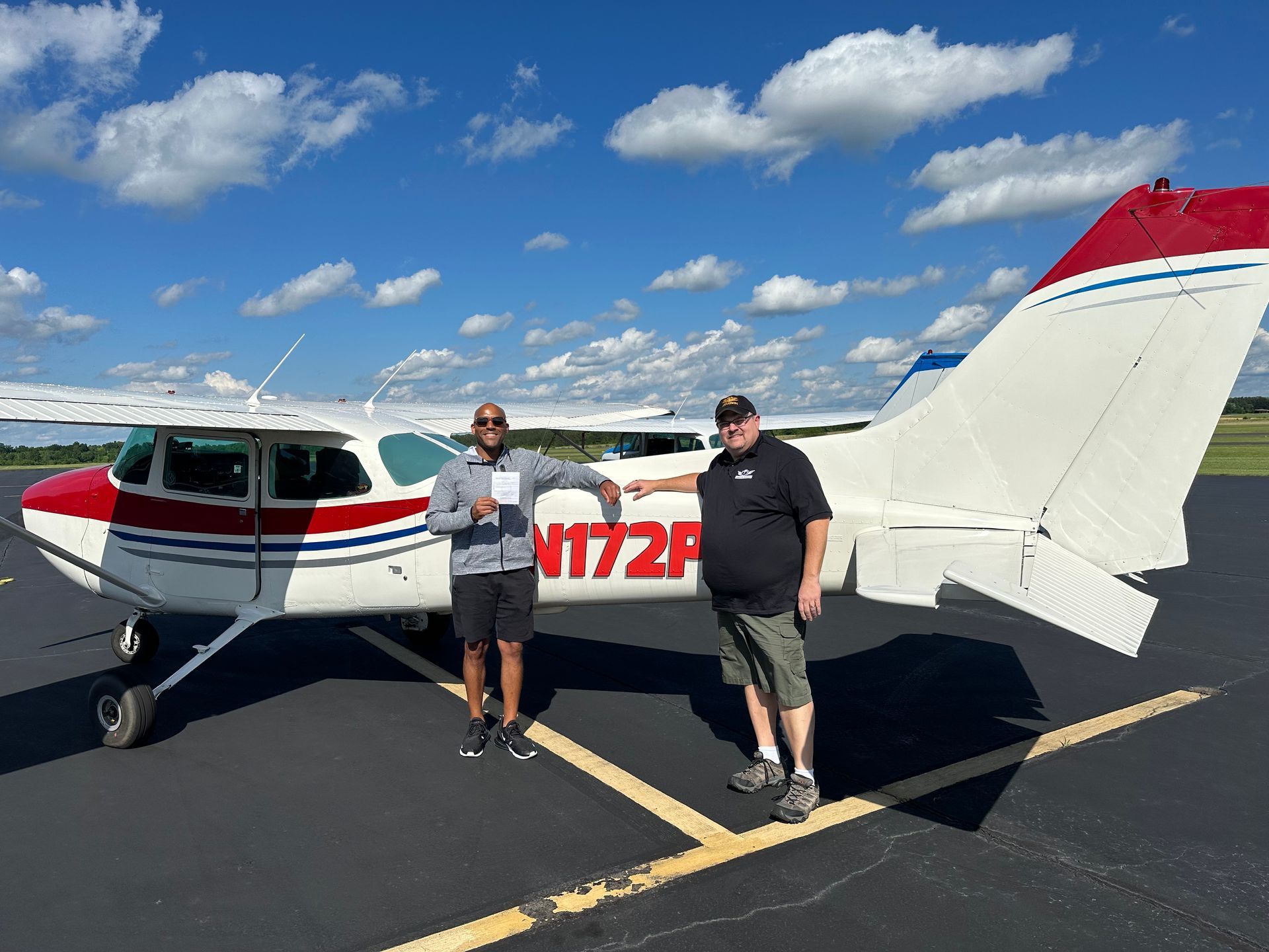 Two men are standing in front of a small plane.