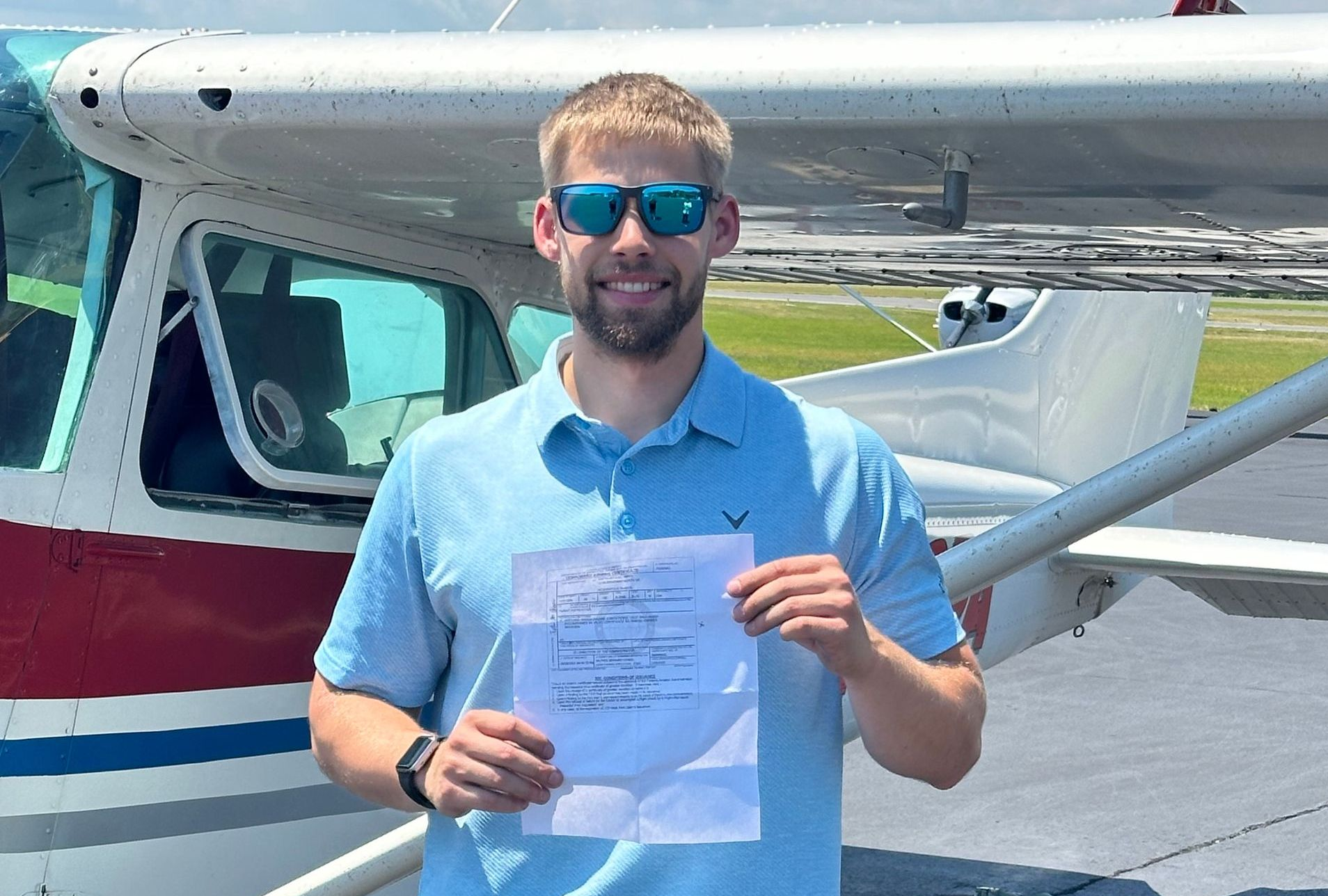 Two men are standing in front of a small plane.