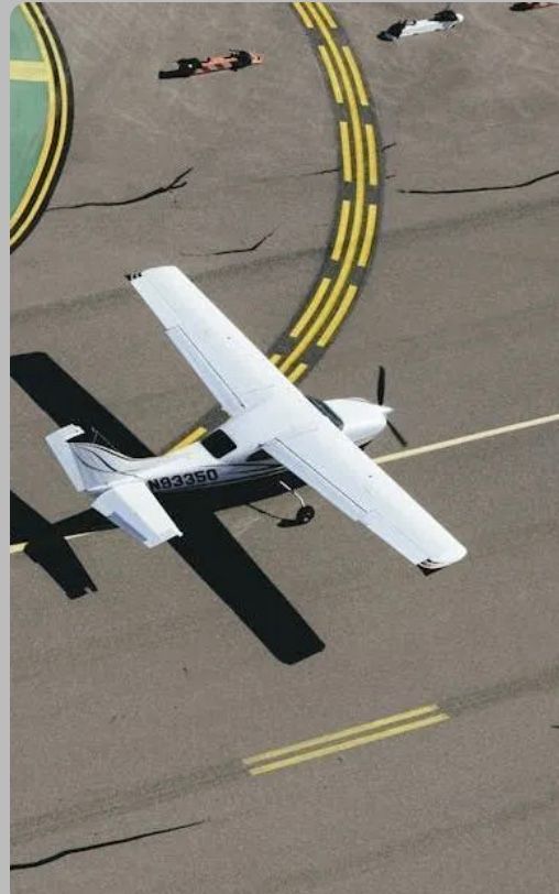 A small plane is sitting on a runway with a yellow line