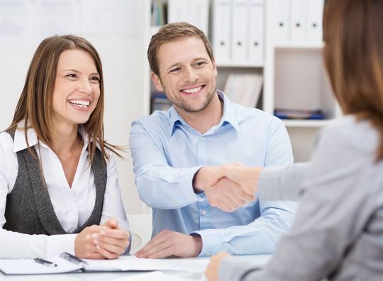 Smiling young man shaking hands with an insurance agent