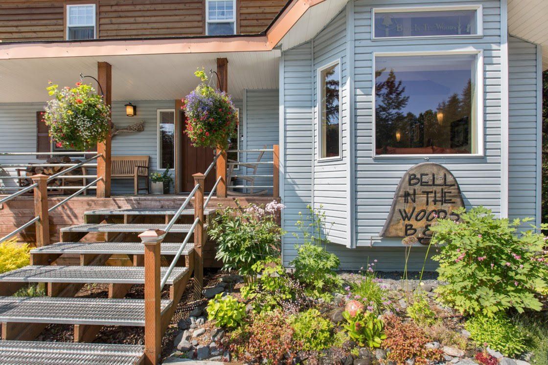 A house with a porch and stairs and a sign that says relax in the woods