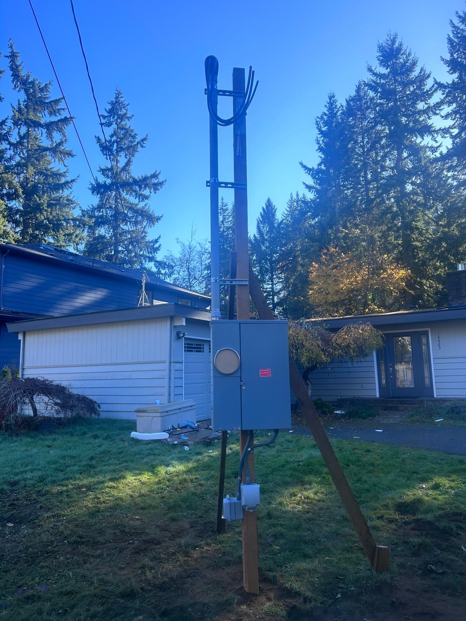Utility pole with electrical equipment in front of a house.