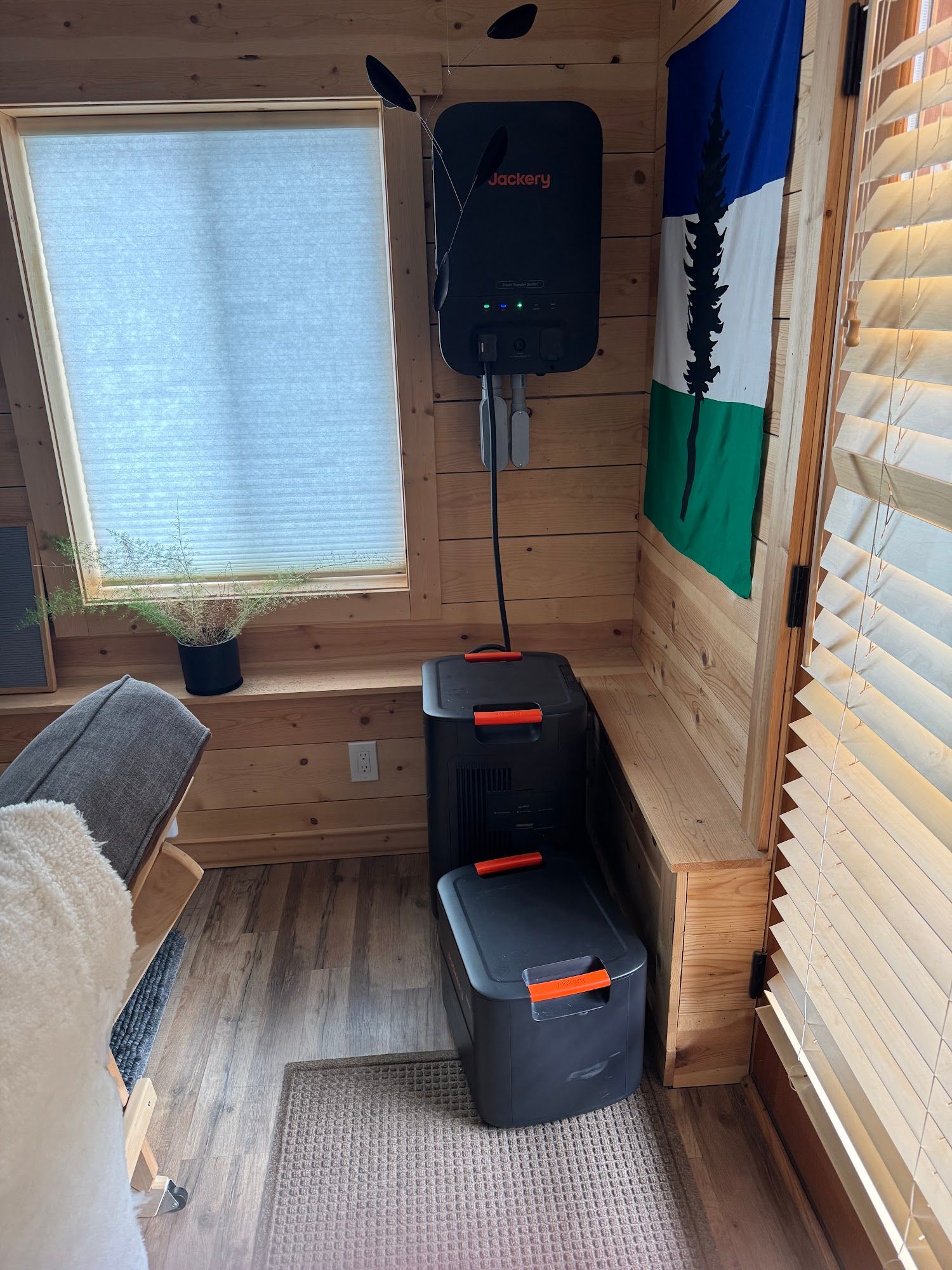 Interior of a wood-paneled room with a solar power system. Window, flag, and bench are also present.