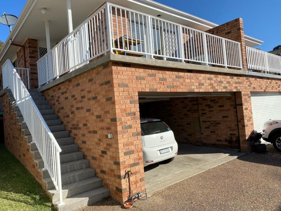 A White Car is Parked in Front of a Brick House — Lifestyle Aluminium Fabrication In Shellharbour, NSW