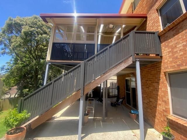 A Staircase Leading Up to a Balcony on the Side of a Brick Building — Lifestyle Aluminium Fabrication In Kiama, NSW