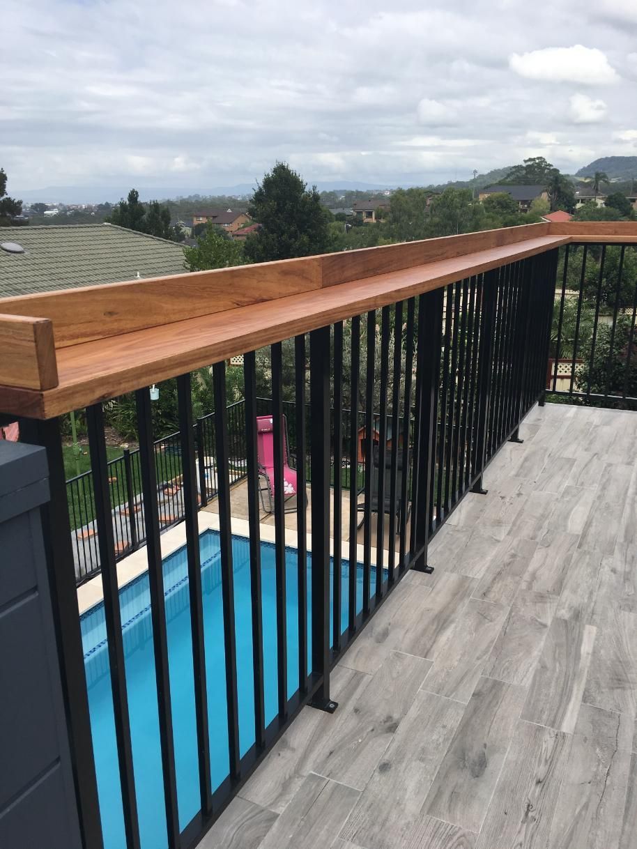 A Balcony Overlooking a Swimming Pool With a Wooden Railing — Lifestyle Aluminium Fabrication In Shellharbour, NSW