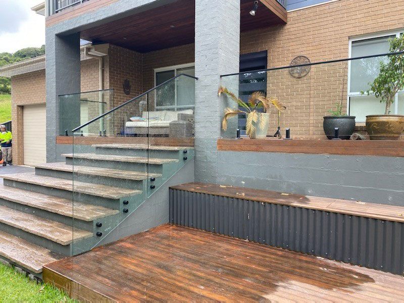 A House With A Wooden Deck And Stairs With A Glass Railing — Lifestyle Aluminium Fabrication In Albion Park Rail, NSW