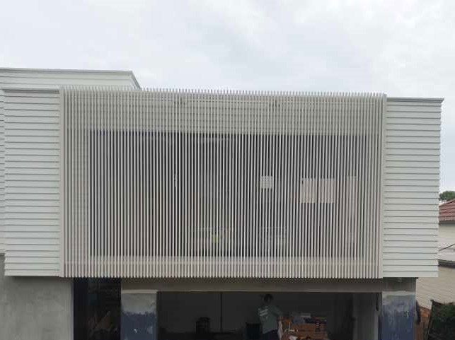 A Man Is Standing In Front Of A White House With A Large Window  — Lifestyle Aluminium Fabrication In Albion Park Rail, NSW