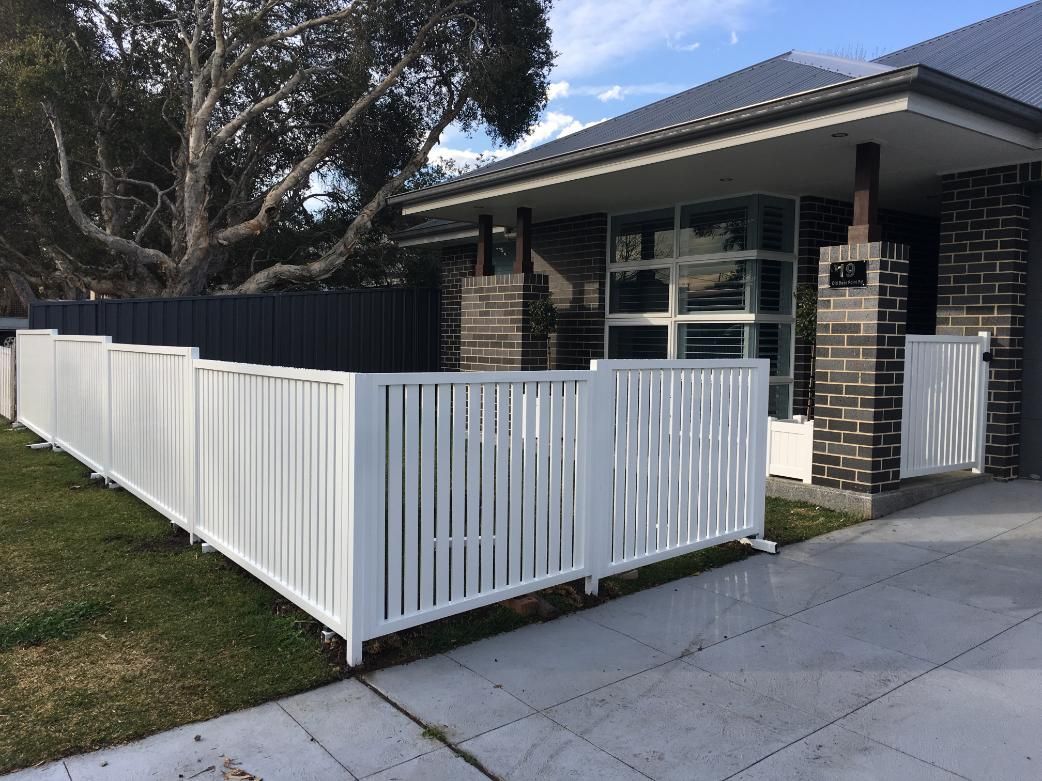 A White Fence is in Front of a Brick House  — Lifestyle Aluminium Fabrication In Dapto, NSW