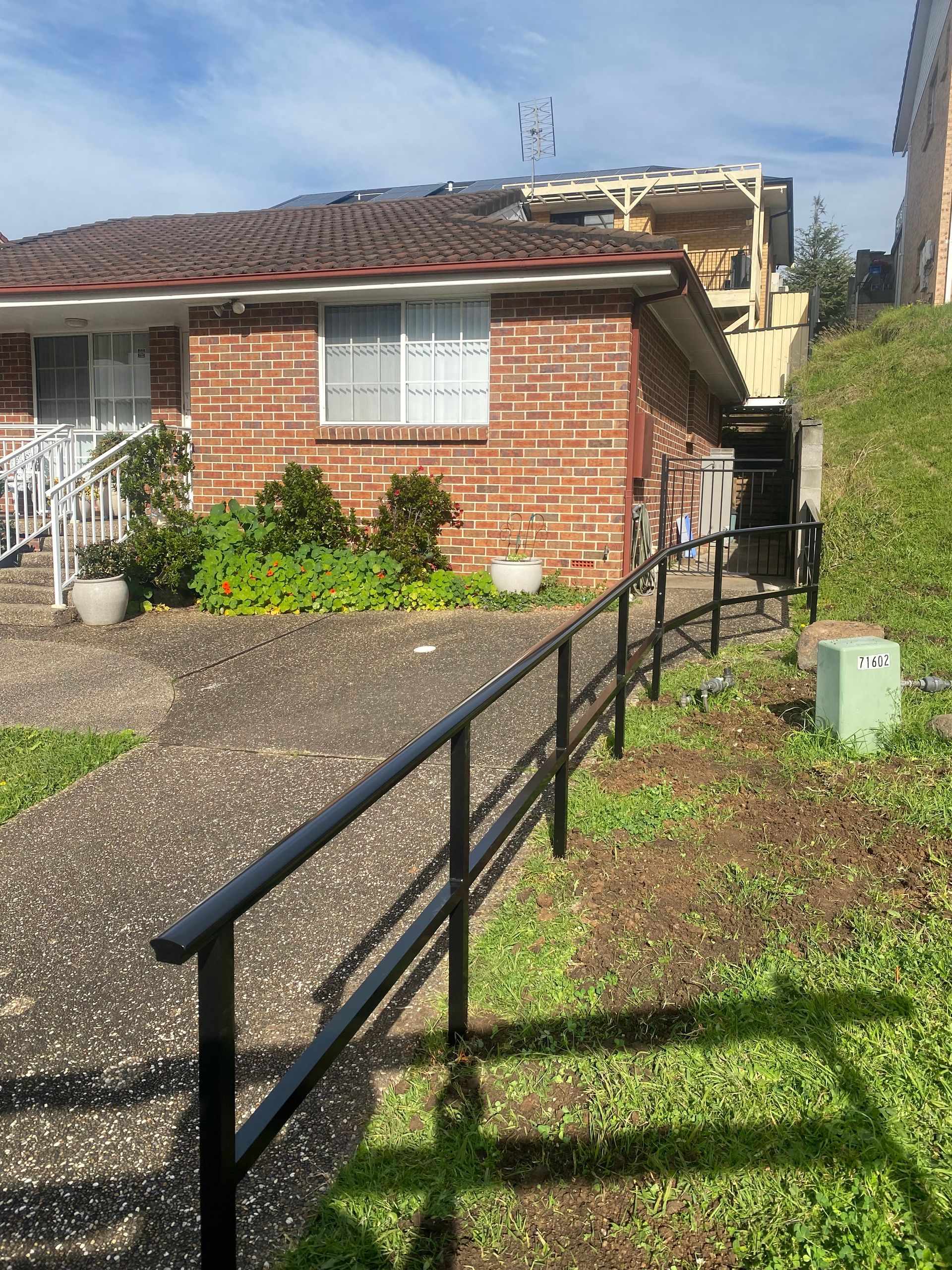 A brick house with a black railing in front of it.