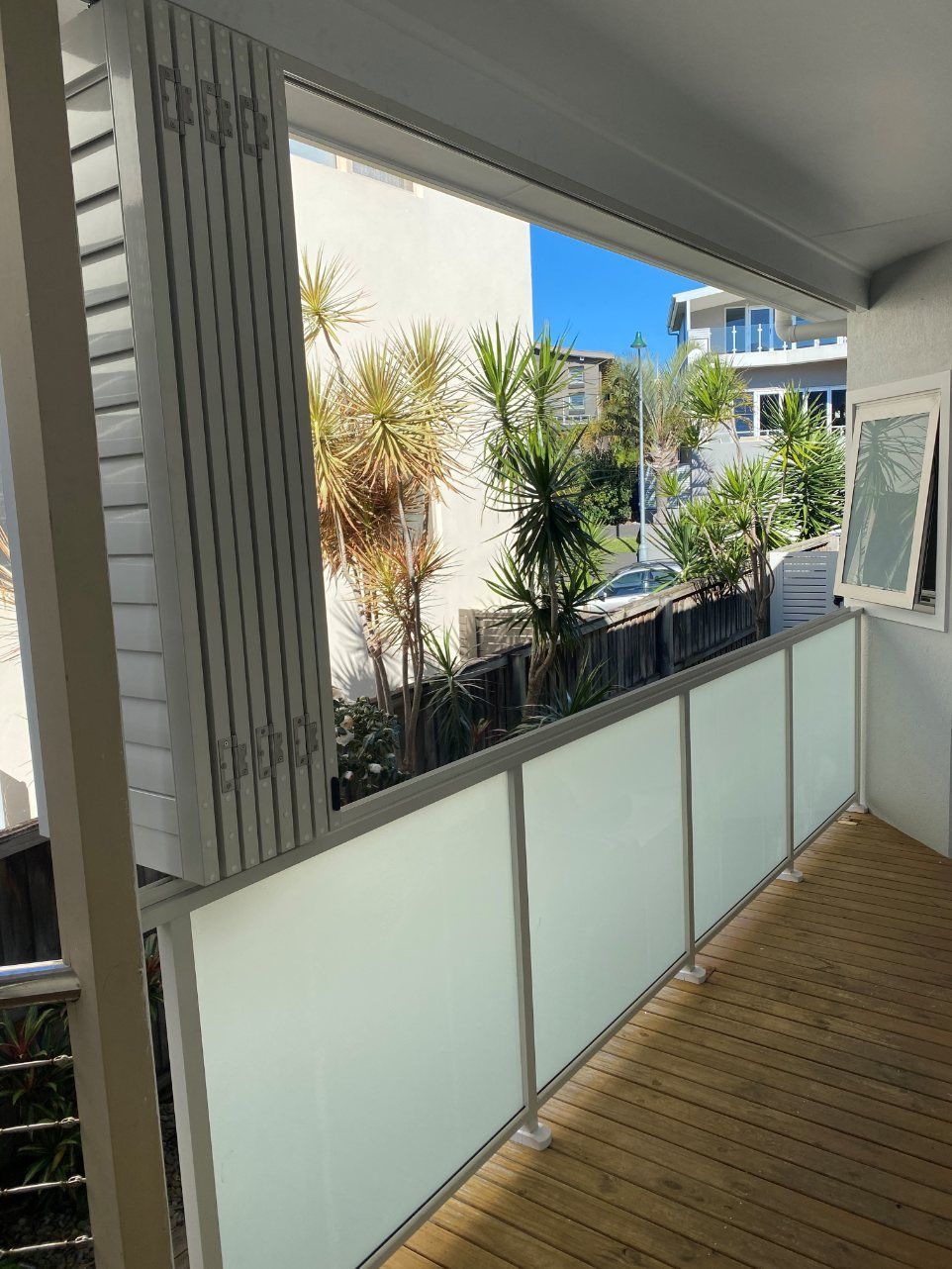 A Balcony with A White Railing and A Window with A View of A City — Lifestyle Aluminium Fabrication In Albion Park Rail, NSW