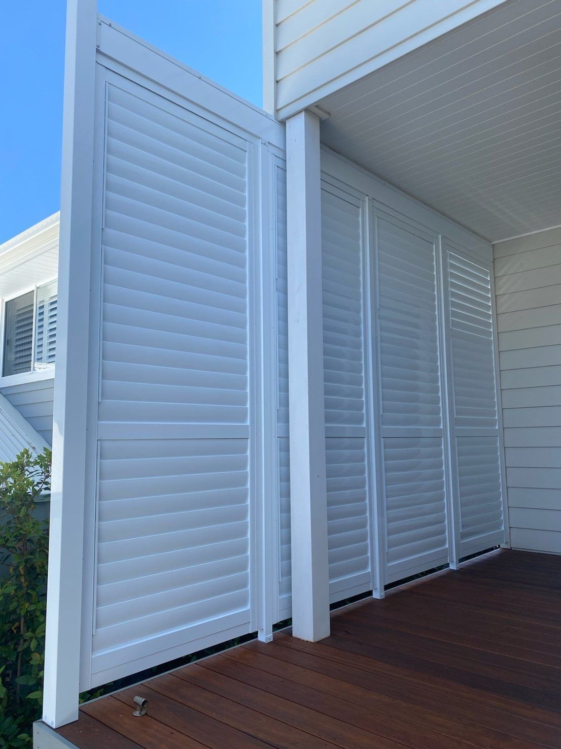 A White Shutter Is on The Side of A Building Next to A Wooden Deck — Lifestyle Aluminium Fabrication In Albion Park Rail, NSW