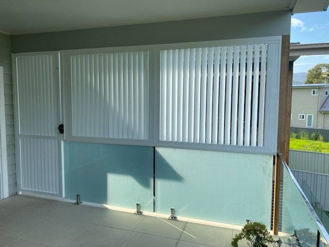 A Balcony with A Glass Railing and White Blinds — Lifestyle Aluminium Fabrication In Albion Park Rail, NSW