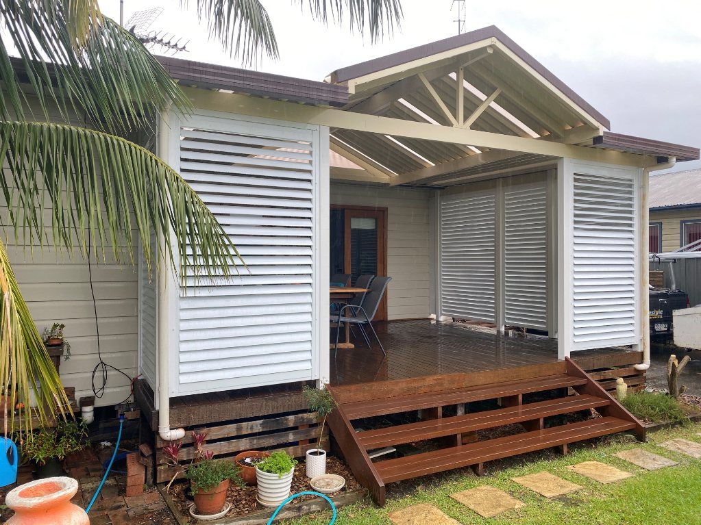 A White House with A Wooden Deck and Stairs in Front of It — Lifestyle Aluminium Fabrication In Albion Park Rail, NSW