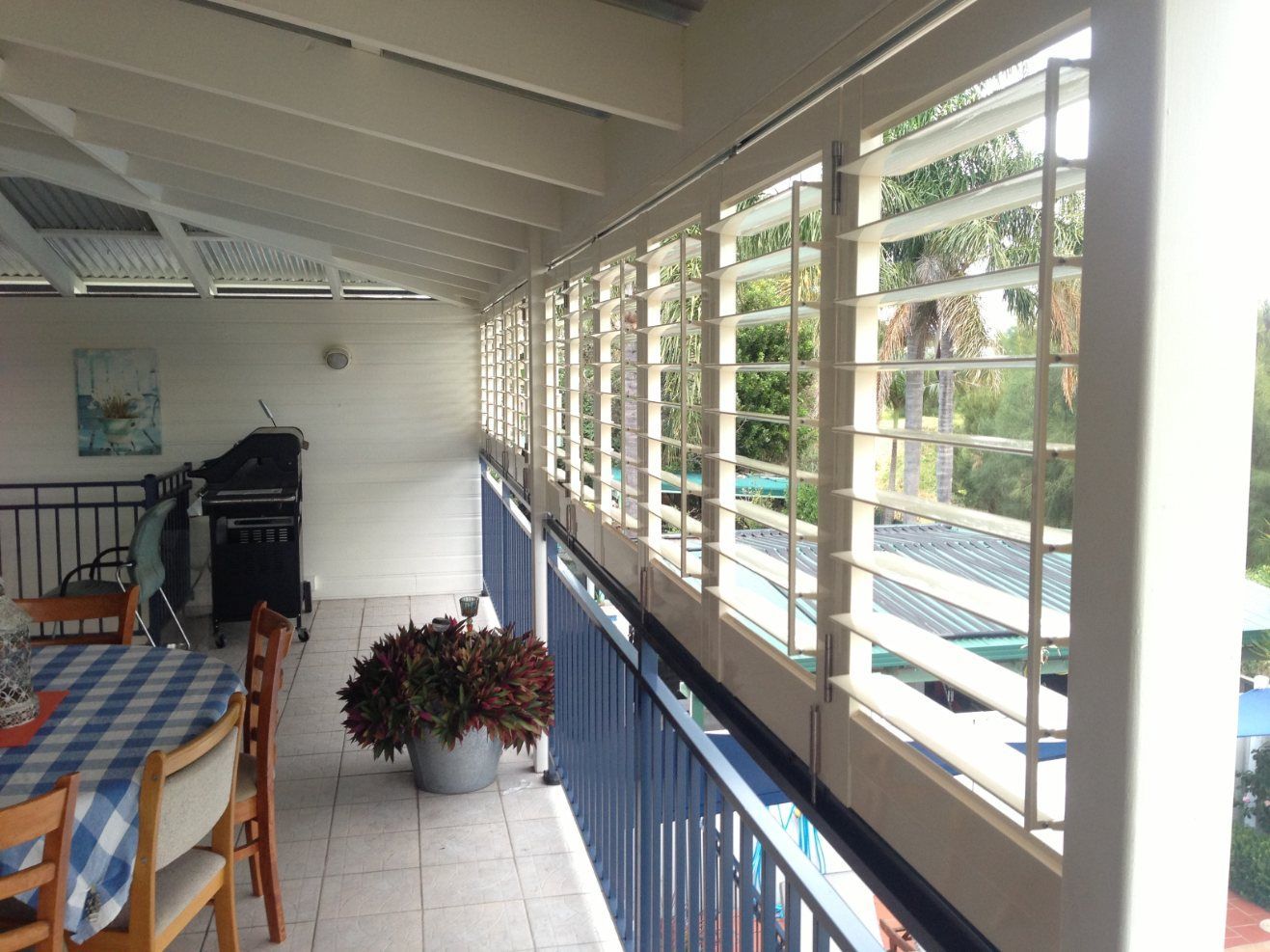 A Balcony with A Table and Chairs and A Blue Railing — Lifestyle Aluminium Fabrication In Albion Park Rail, NSW